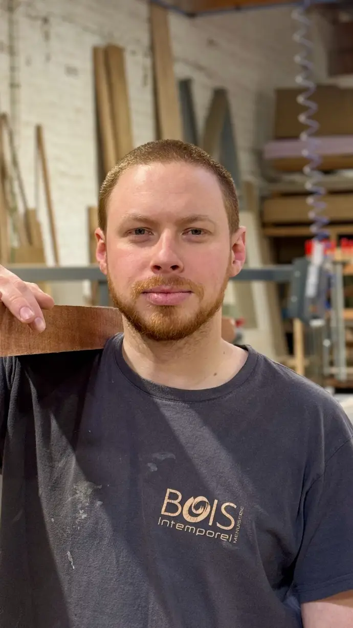 Audric Penna, menuisier, qui porte une planche en bois