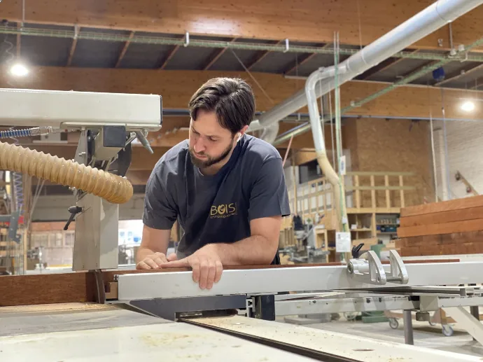 Loïc Penna, menuisier, qui coupe une planche en bois massif