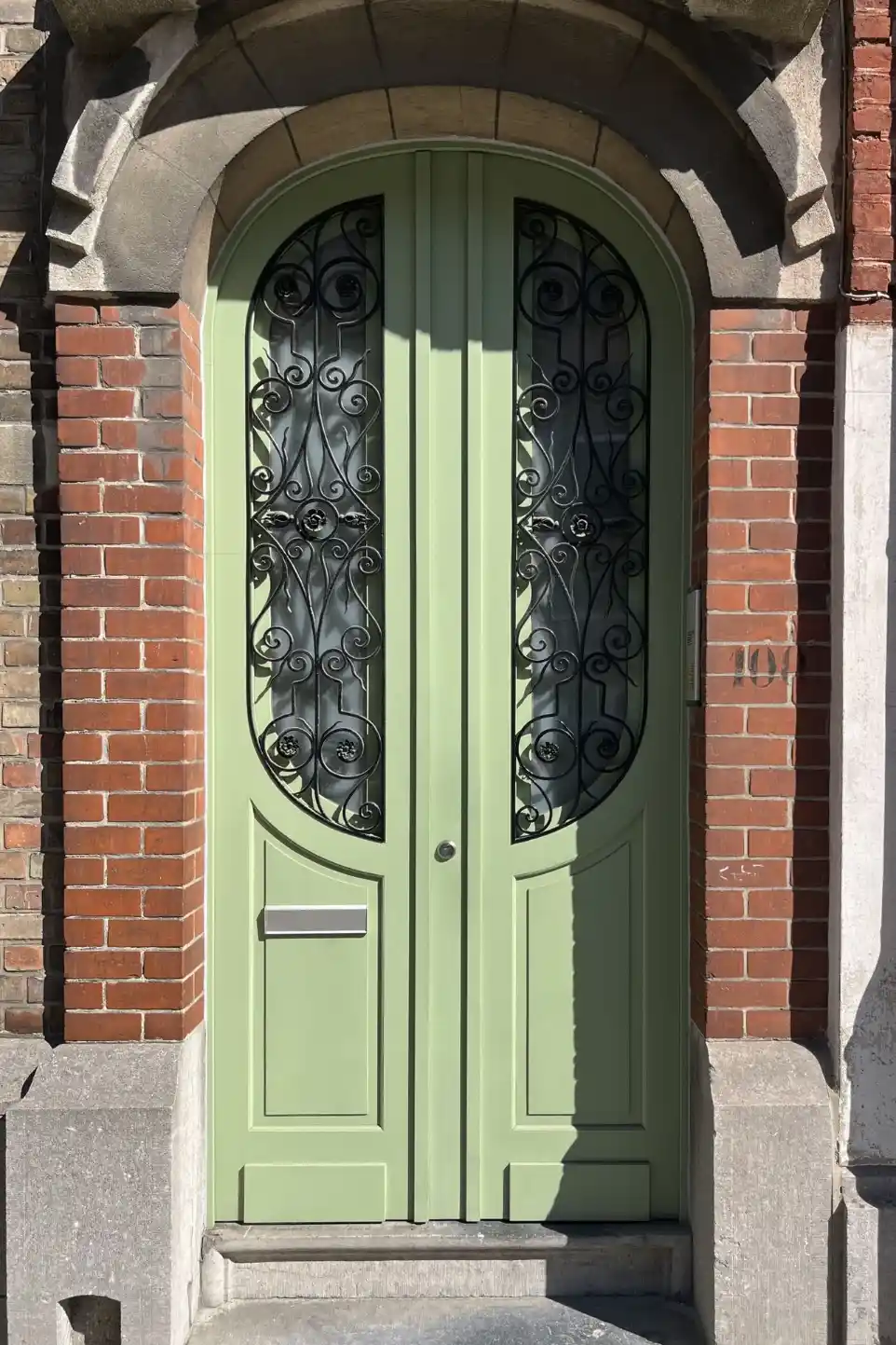 Double porte d'entrée verte arrondie avec fer forgé