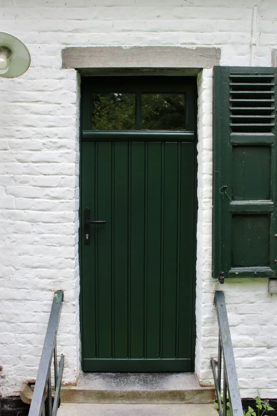 Porte d'entrée verte à planchettes et imposte pour une ferme