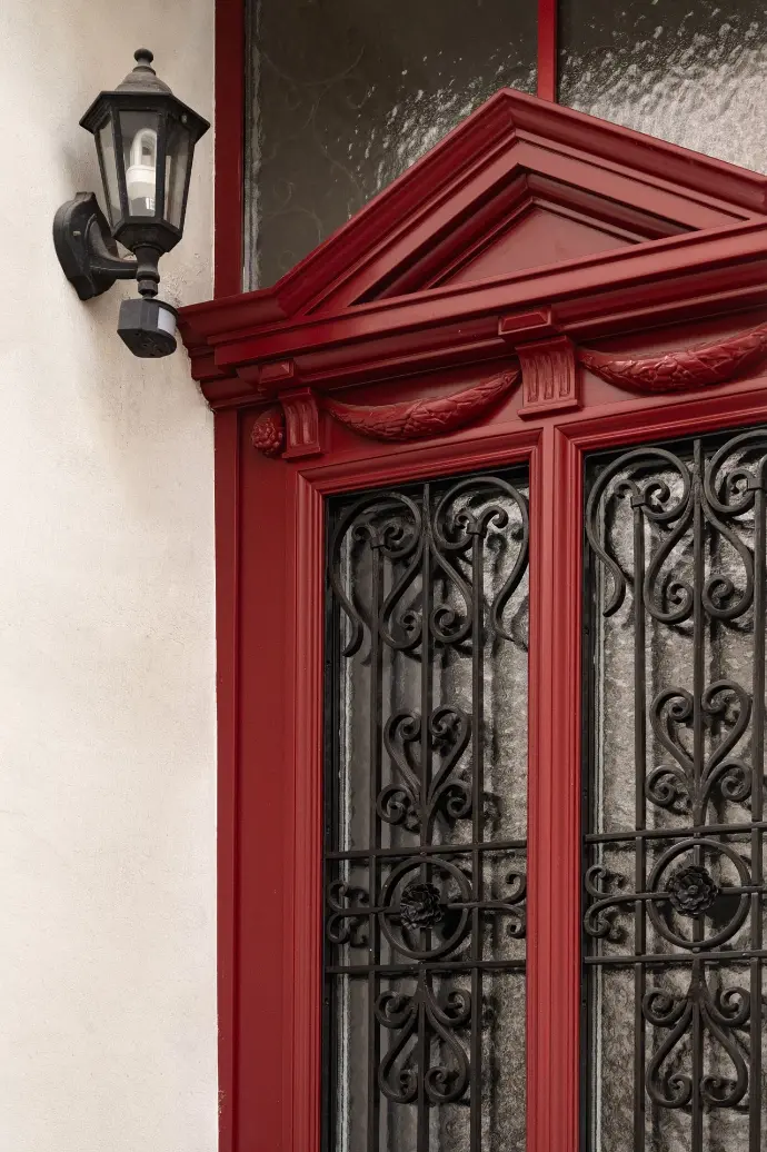 Porte d'entrée rouge sculptée avec fer forgé