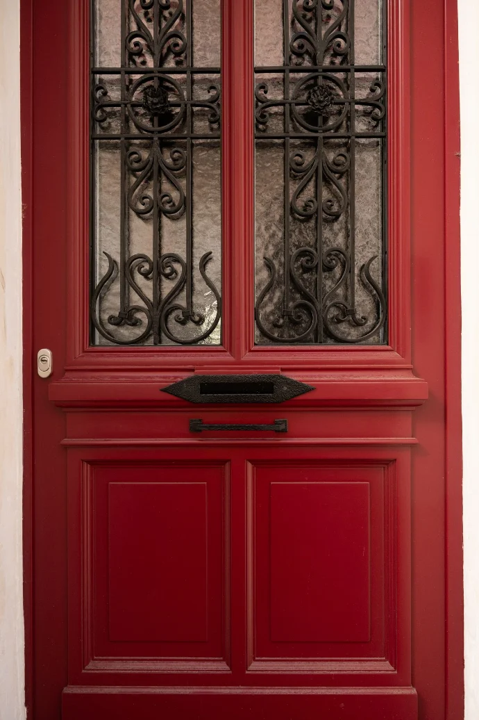 Porte d'entrée rouge sculptée avec fer forgé