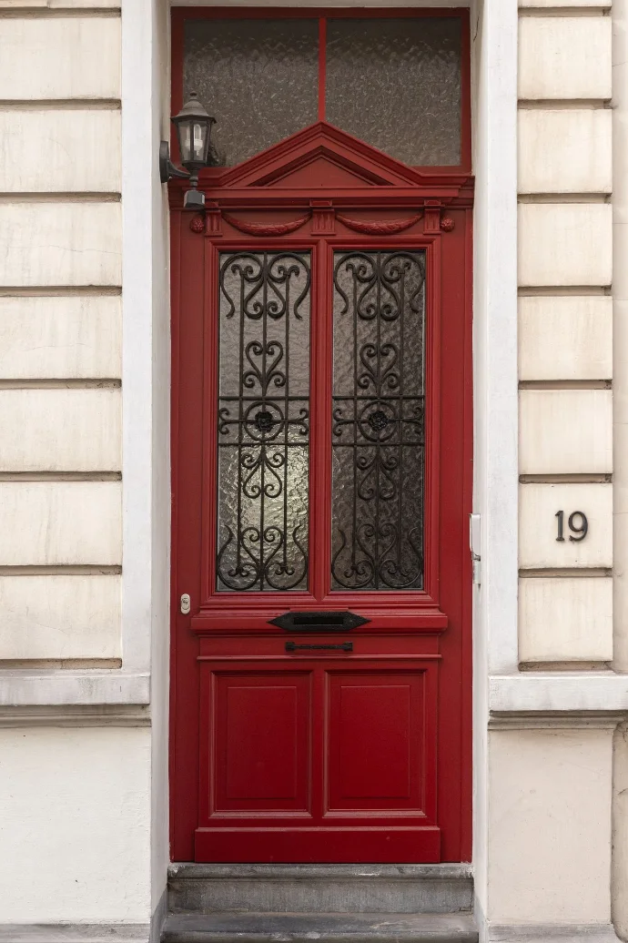 Porte d'entrée rouge sculptée avec fer forgé